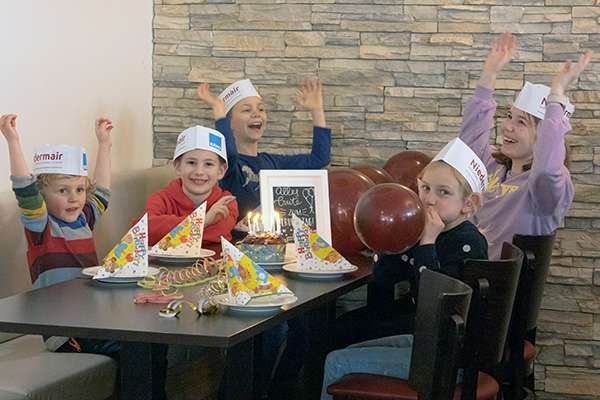 Fröhliche Kinder am Tisch an einem Kindergeburtstag in der Bäckerei Niedermair in Diedorf